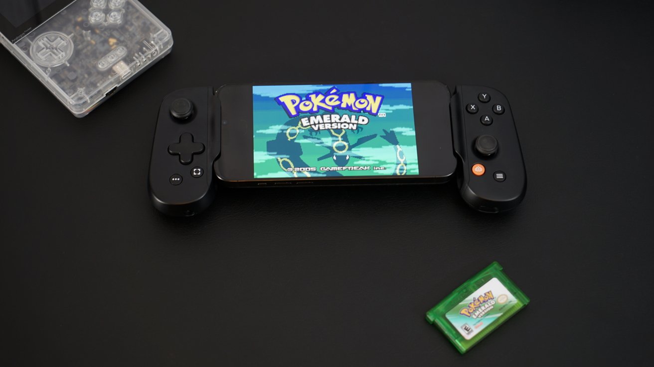 iPhone v rukojeti ovladače s nápisem „Pokémon Emerald“ na obrazovce