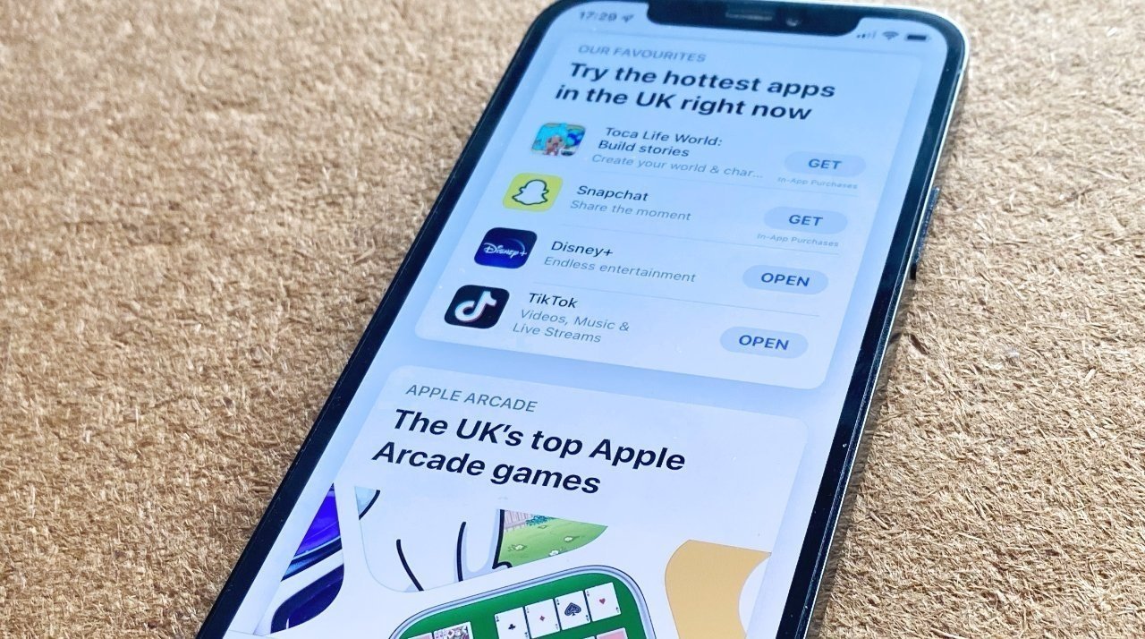 Obrázek iPhonu na koberci s otevřenou britskou verzí App Store