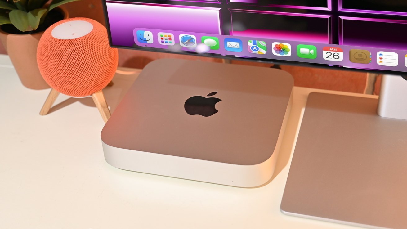 Mac mini na stole vedle chytrého reproduktoru a monitoru s rozhraním macOS.