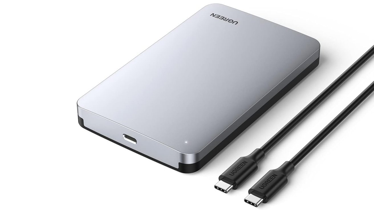 Stříbrný externí pevný disk se značkou UGREEN, jedním vstupním portem USB-C a dvěma kabely typu C na bílém pozadí