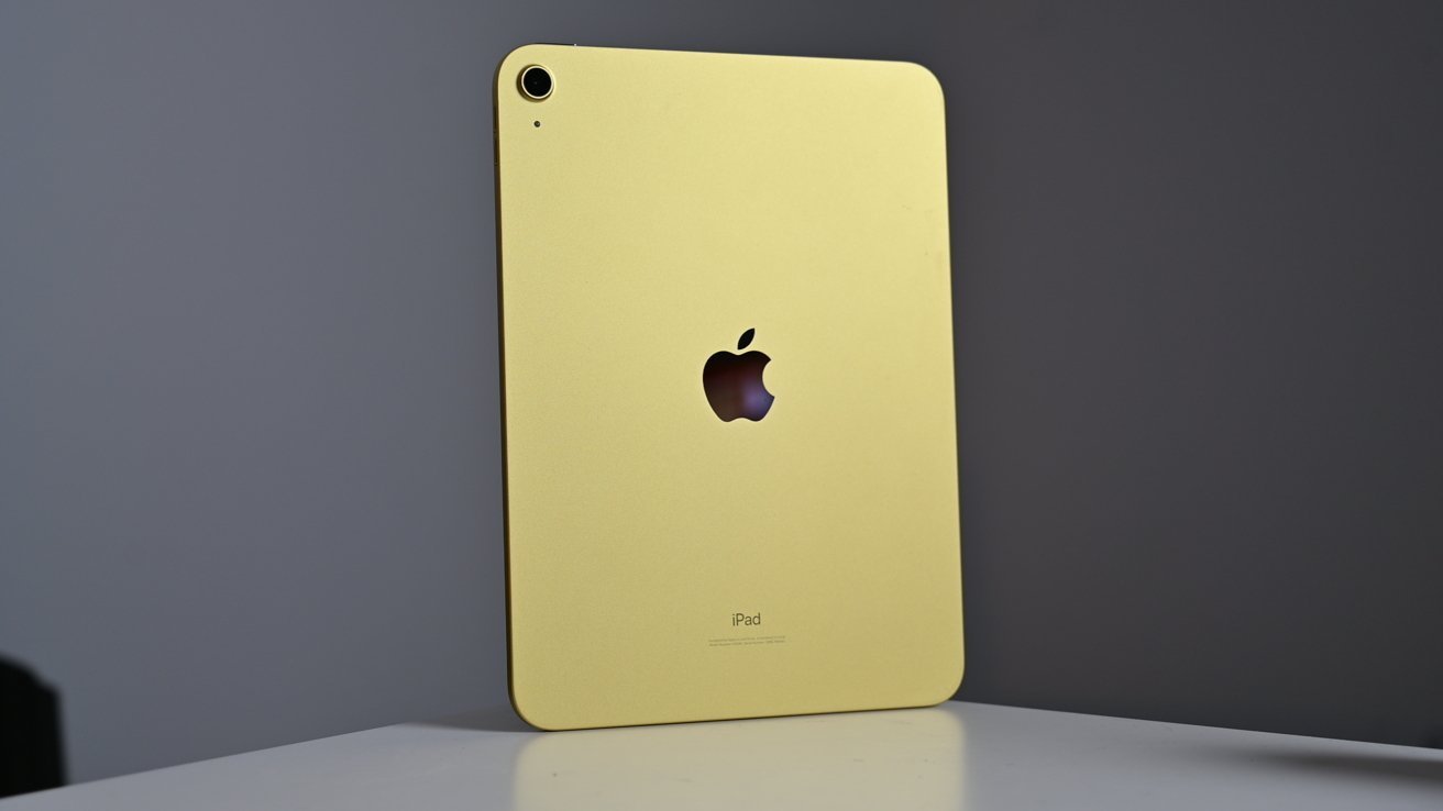 Žlutý Apple iPad stojící vzpřímeně na bílém povrchu, fotoaparát a logo Apple jsou viditelné.