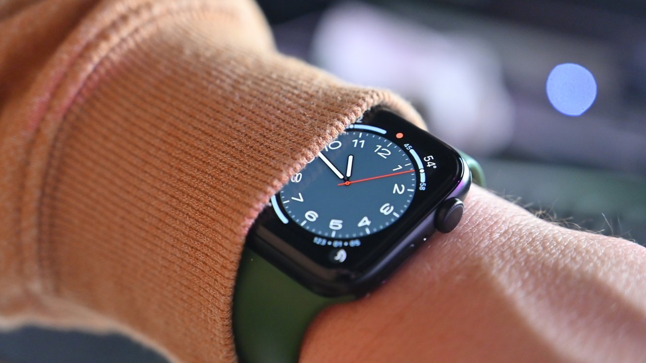 Apple Watch SE 2, částečně zakryté hnědým pouzdrem na zápěstí.